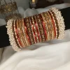 From our Exclusive Collection, this red and maroon bangle set is designed to create an ethereal bridal statement. It features a rich combination of dotted metal bangles in deep maroon, glossy red bangles, and intricate rice work kary in white, maroon, and champagne shades. The look is beautifully finished with luxurious shahi gajray on both ends for a complete royal touch.Perfect for bridal wear, engagement, festive occasions, and traditional events. Deep red and maroon colour palette • Dotted metal bangles • Glossy red finish bangles • Intricate rice work kary • White, maroon, and champagne detailing • Shahi gajray finishing Material Details Bangles: High-quality brass alloy Kary work: Copper alloy Stones & embellishments: Non-precious, premium quality materials Durable, lightweight, and crafted for elegant long wear.