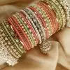 Gulabi is an exclusive handcrafted bangle set featuring a soft blend of mint green, blush pink, and champagne tones. Designed with intricate kundan kary, pearl detailing, teardrop stone accents, and a statement jhumki charm, this set is beautifully finished with luxurious shahi gajray on both ends for a complete bridal look.Perfect for nikkah, engagement, mehndi, walima, and festive occasions. Base Bangles: High-quality brass alloy Kary Work: Copper alloy Stones & Pearls: Non-precious, premium quality stones and artificial pearls Durable, lightweight, and crafted for comfortable long wear.