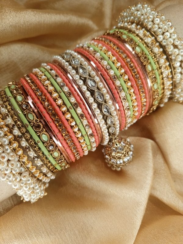 Gulabi is an exclusive handcrafted bangle set featuring a soft blend of mint green, blush pink, and champagne tones. Designed with intricate kundan kary, pearl detailing, teardrop stone accents, and a statement jhumki charm, this set is beautifully finished with luxurious shahi gajray on both ends for a complete bridal look.Perfect for nikkah, engagement, mehndi, walima, and festive occasions. Base Bangles: High-quality brass alloy Kary Work: Copper alloy Stones & Pearls: Non-precious, premium quality stones and artificial pearls Durable, lightweight, and crafted for comfortable long wear.