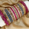 Chamkeli is a vibrant handcrafted bangle set featuring intricate rice work kary in pink and royal blue tones tear dep kundun jhumki The stack is beautifully balanced with detailed stone embellishments and finished with bold magenta gajra on both ends for a rich, statement bridal look. Perfect for mehndi, baraat, engagement, and festive celebrations where colour and elegance come together.