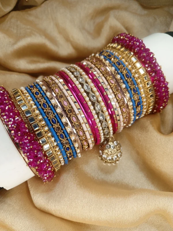 Chamkeli is a vibrant handcrafted bangle set featuring intricate rice work kary in pink and royal blue tones tear dep kundun jhumki The stack is beautifully balanced with detailed stone embellishments and finished with bold magenta gajra on both ends for a rich, statement bridal look. Perfect for mehndi, baraat, engagement, and festive celebrations where colour and elegance come together.