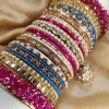Chamkeli is a vibrant handcrafted bangle set featuring intricate rice work kary in pink and royal blue tones tear dep kundun jhumki The stack is beautifully balanced with detailed stone embellishments and finished with bold magenta gajra on both ends for a rich, statement bridal look. Perfect for mehndi, baraat, engagement, and festive celebrations where colour and elegance come together.