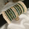 Noor – dark green A striking bridal set featuring a Reverse American Diamond Jhumki Kara, Premium Shahi Gajray with golden accents, and matching Indian Sikka Work Karay. Layered with thin karay in pearls, crystals, and wire work, paired with matte and glossy bangles in rich maroon and gold tones. Ideal for weddings, valima, and festive celebrations.
