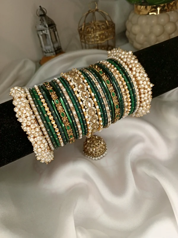 Noor – dark green A striking bridal set featuring a Reverse American Diamond Jhumki Kara, Premium Shahi Gajray with golden accents, and matching Indian Sikka Work Karay. Layered with thin karay in pearls, crystals, and wire work, paired with matte and glossy bangles in rich maroon and gold tones. Ideal for weddings, valima, and festive celebrations.