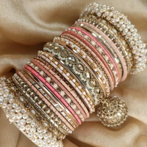Noor – Shades of Peach A bridal statement set featuring a Reverse American Diamond Jhumki Kara, Premium Shahi Gajray with golden accents, and matching Indian Sikka Work Karay. Enhanced with thin karay in pearls, crystals, and wire work, paired with matte and glossy bangles in elegant peach tones. Perfect for weddings, valima, and special celebrations.