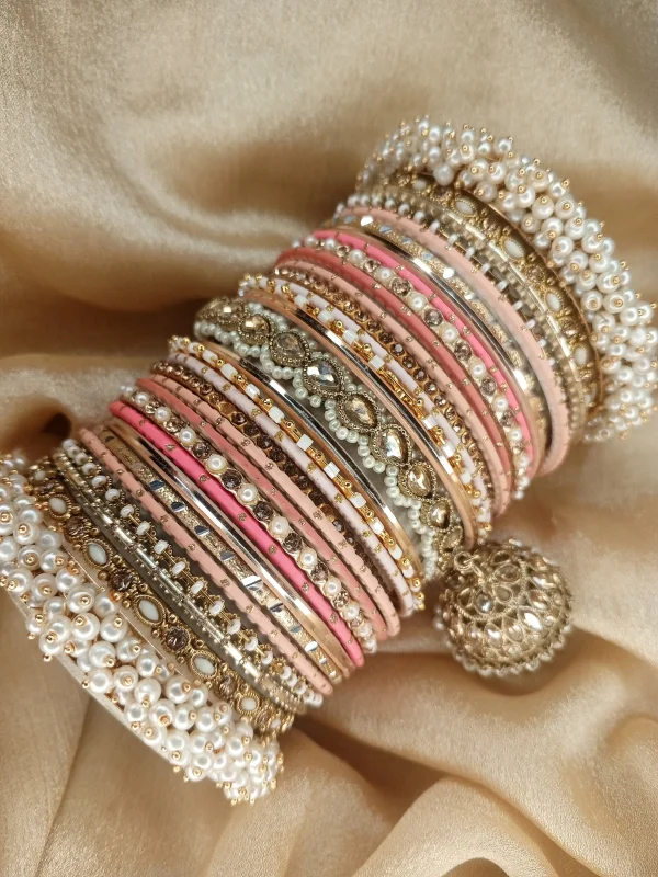 Noor – Shades of Peach A bridal statement set featuring a Reverse American Diamond Jhumki Kara, Premium Shahi Gajray with golden accents, and matching Indian Sikka Work Karay. Enhanced with thin karay in pearls, crystals, and wire work, paired with matte and glossy bangles in elegant peach tones. Perfect for weddings, valima, and special celebrations.