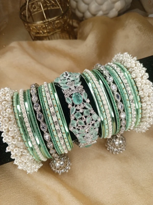 Exclusive Mint Green & Silver Set ✨Elevate your bridal or festive look with our exquisite mint green and silver bangle set! Featuring a center mint green & silver kara, paired with two teardrop kundan jhumki karas and pearl-accented silver Shahi Gajray, this set blends elegance and tradition perfectly.Perfect for weddings, valima ceremonies, and special celebrations.