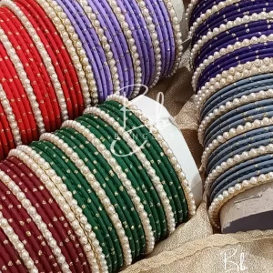 Elevate your festive ensemble with our most-trending Elara set. Perfectly balancing tradition with a clean, sophisticated aesthetic, this set is an essential for your Eid bangles collection. Featuring a classic dozen-bangle core accented by our signature 7 pearl chori dividers, it offers a refined sparkle that transitions effortlessly from formal weddings to intimate
