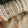 Hoor is a handcrafted white and gold bridal bangle set featuring intricate kundan kary, elegant teardrop stone detailing, a statement teardrop jhumki charm, and sahi pearl gajray on both ends. Perfect for bridal, nikkah, walima, and festive wear. • White and gold classic combination • Detailed kundan kary work • Teardrop crystal stones • Attached jhumki charm • Sahi pearl gajray finish